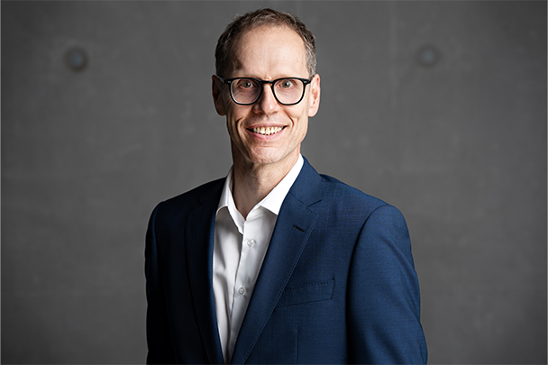 Close-up von Markus Stammen vor einer dunkel grauen Betonwand