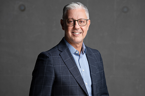 Close-up von Martin Lugertvor einer dunkel grauen Betonwand